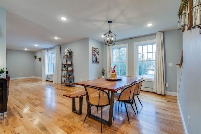 dining area with a chandelier, a baseboard radiator, and light hardwood / wood-style flooring