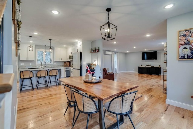 dining area with light hardwood / wood-style floors and an inviting chandelier