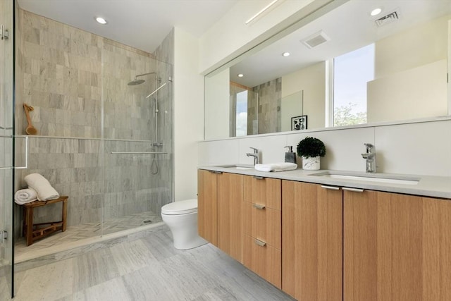 bathroom featuring vanity, toilet, tiled shower, and tile walls