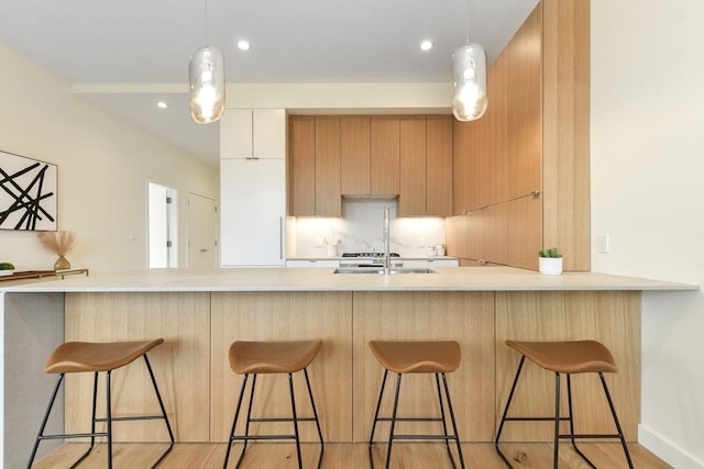 kitchen featuring decorative light fixtures, white cabinetry, kitchen peninsula, and light wood-type flooring