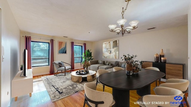 dining area with an inviting chandelier, wood finished floors, and visible vents