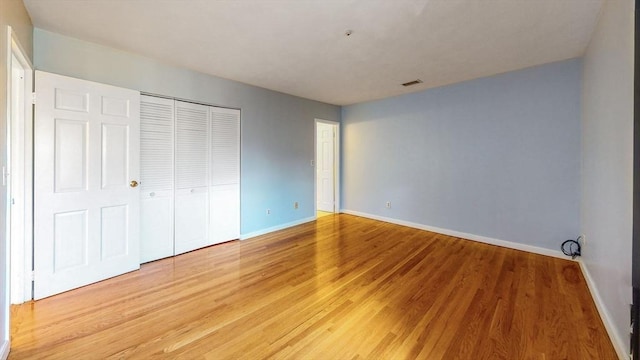 unfurnished bedroom featuring visible vents, baseboards, a closet, and light wood finished floors