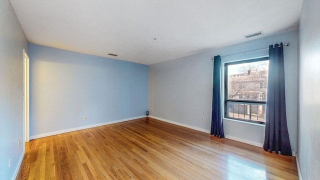 empty room featuring light wood finished floors, visible vents, and baseboards