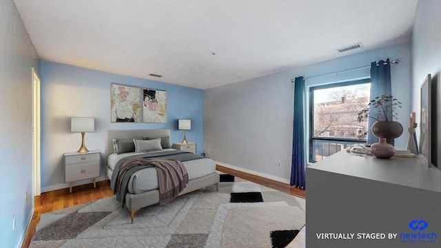 bedroom with wood finished floors, visible vents, and baseboards