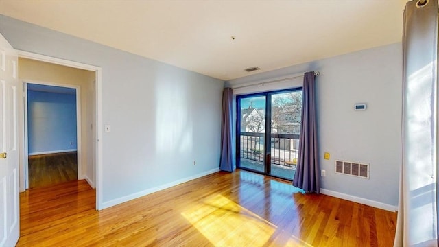 unfurnished room featuring light wood-type flooring, visible vents, and baseboards