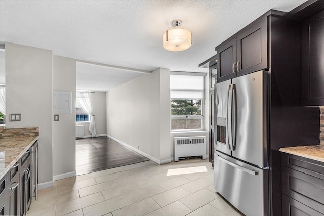 280 Boylston St Unit 511, Newton, MA 02467 - kitchen with radiator heating unit, stainless steel fridge with ice dispenser, light stone counters, baseboards, and a textured ceiling