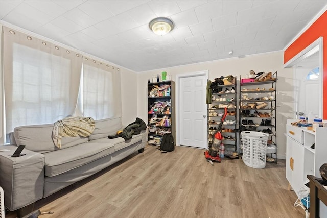 living area with light hardwood / wood-style flooring and crown molding