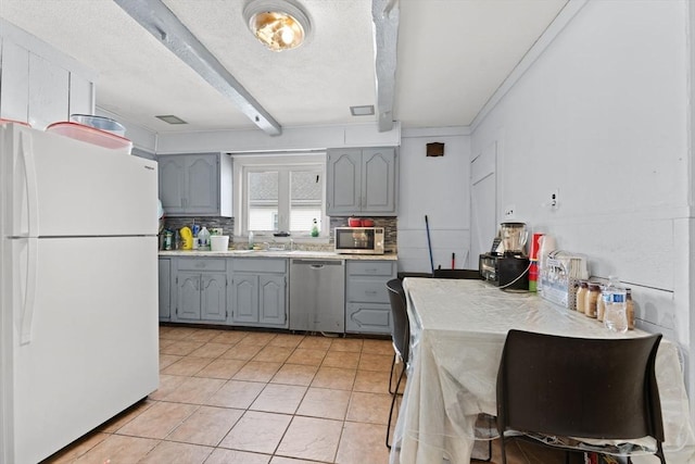 kitchen featuring appliances with stainless steel finishes, gray cabinetry, and beam ceiling