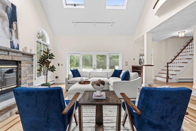 26 Emery Ct, Stoneham, MA 02180 - living room featuring rail lighting, high vaulted ceiling, a baseboard heating unit, a skylight, and healthy amount of natural light