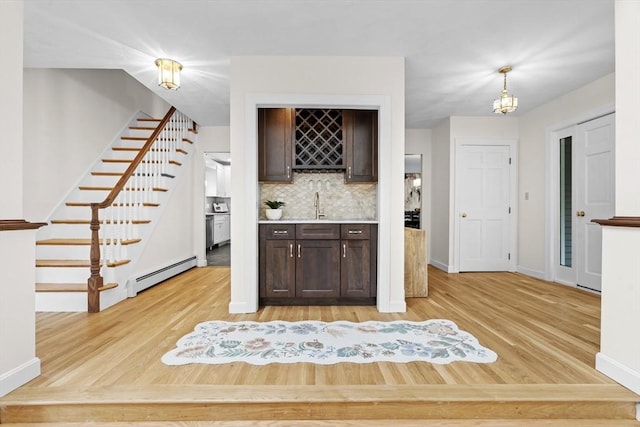 26 Emery Ct, Stoneham, MA 02180 - kitchen featuring a baseboard radiator, dark brown cabinets, light wood-type flooring, and tasteful backsplash