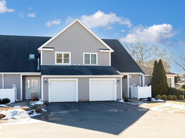 traditional-style house with fence, driveway, a shingled roof, and a garage