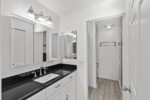 bathroom featuring vanity, wood finished floors, a stall shower, baseboards, and a closet