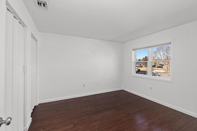 unfurnished bedroom featuring dark wood finished floors, baseboards, and visible vents