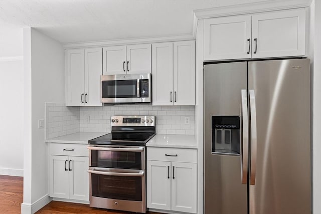 kitchen featuring stainless steel appliances, white cabinetry, wood finished floors, and decorative backsplash