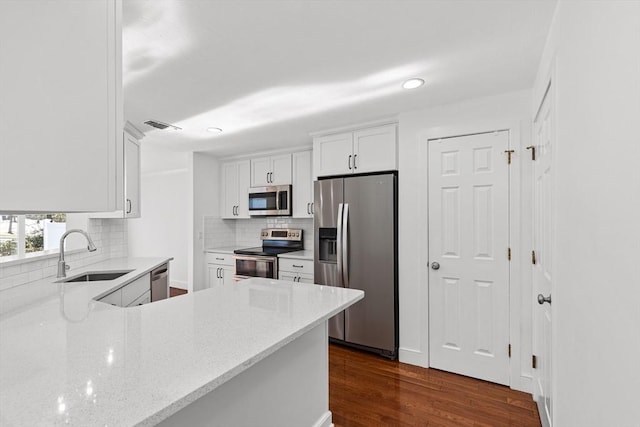 kitchen featuring appliances with stainless steel finishes, visible vents, white cabinets, a sink, and light stone counters