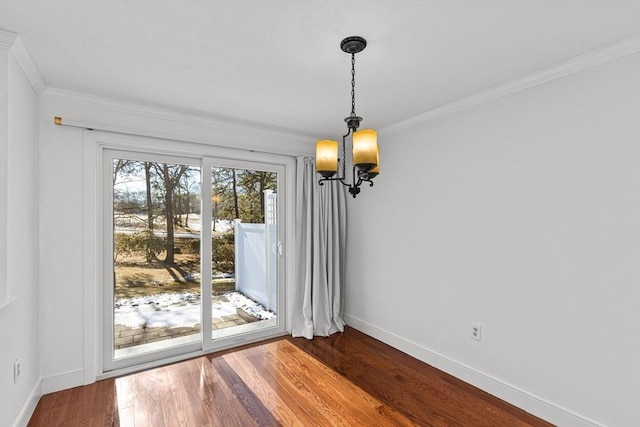 unfurnished dining area with baseboards, crown molding, and wood finished floors