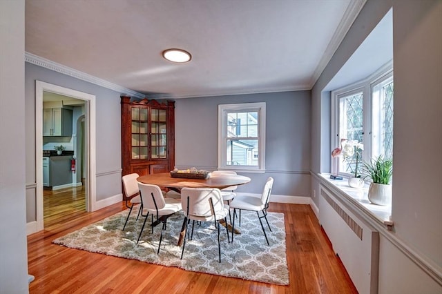 dining area with light hardwood / wood-style floors, ornamental molding, and a healthy amount of sunlight