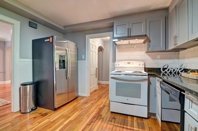 kitchen featuring tasteful backsplash, light hardwood / wood-style floors, stainless steel appliances, dark stone countertops, and gray cabinets