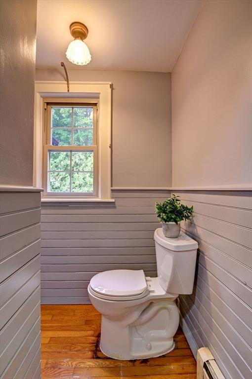 bathroom featuring toilet, wood-type flooring, and a baseboard heating unit