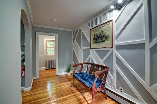 living area featuring radiator heating unit, ornamental molding, and light hardwood / wood-style flooring