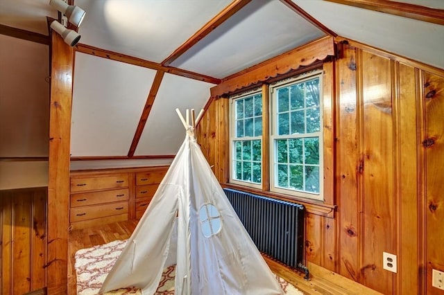 interior space with radiator heating unit, hardwood / wood-style flooring, vaulted ceiling, and wooden walls