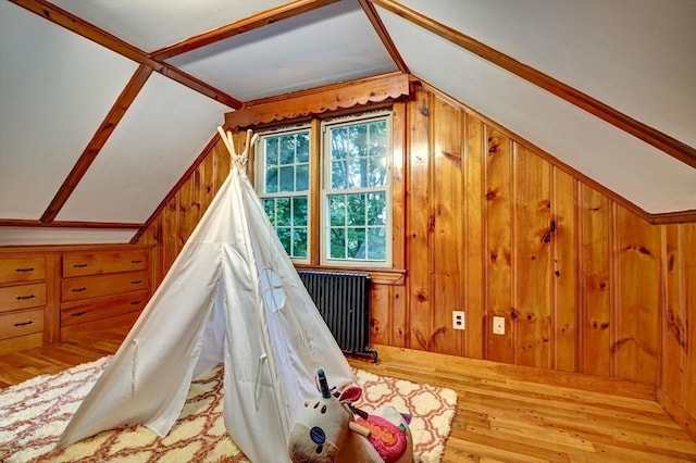 game room featuring wooden walls, radiator heating unit, hardwood / wood-style floors, and lofted ceiling