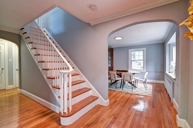 stairs with hardwood / wood-style flooring and ornamental molding