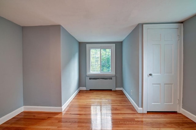 additional living space featuring radiator heating unit and light hardwood / wood-style flooring