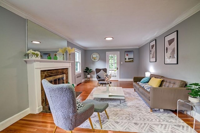 living room with crown molding, a fireplace, and wood-type flooring