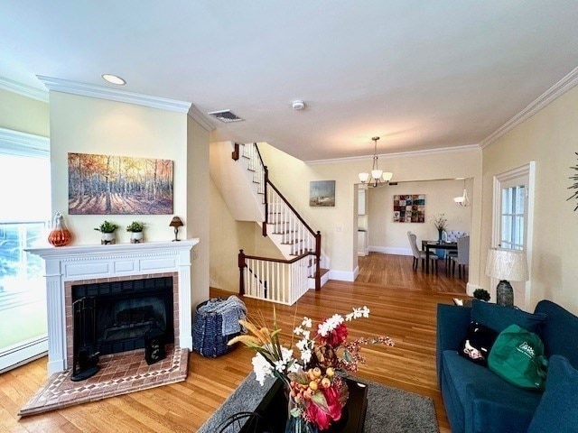 living room with stairway, wood finished floors, visible vents, ornamental molding, and a chandelier