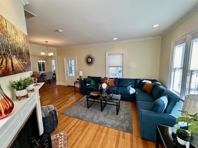 living room with a wealth of natural light, light wood finished floors, and ornamental molding