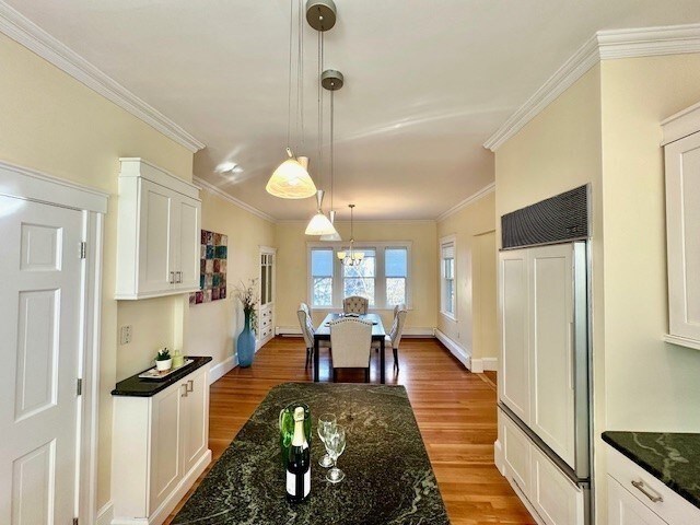 kitchen featuring wood finished floors, paneled built in fridge, ornamental molding, white cabinets, and pendant lighting