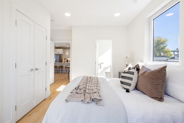 bedroom featuring stainless steel refrigerator and light hardwood / wood-style floors