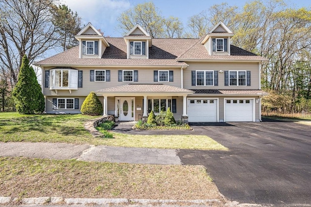 shingle-style home with a garage, a front lawn, aphalt driveway, covered porch, and a shingled roof
