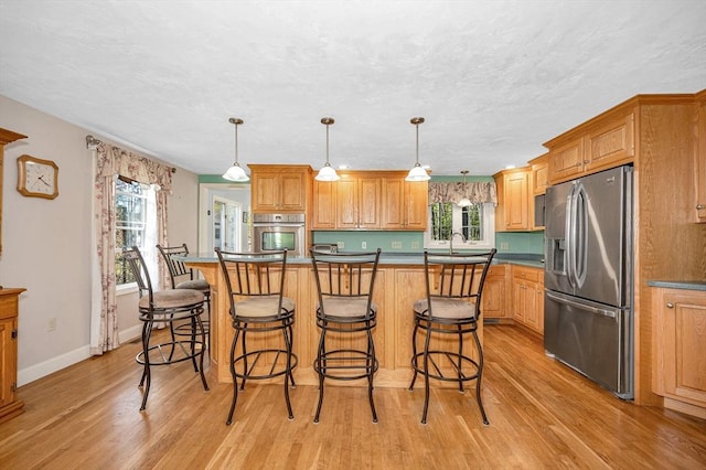 kitchen featuring light wood-type flooring, plenty of natural light, a breakfast bar, and stainless steel appliances