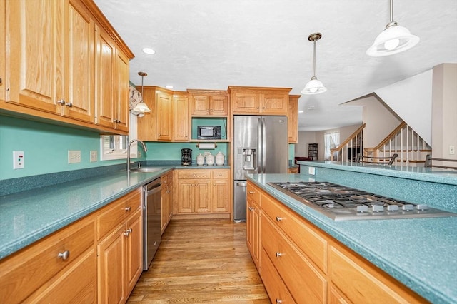 kitchen with appliances with stainless steel finishes, a sink, light wood finished floors, recessed lighting, and pendant lighting