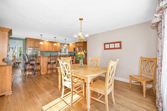 dining space featuring baseboards, light wood-type flooring, and a notable chandelier
