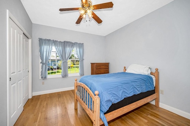 bedroom featuring baseboards, ceiling fan, wood finished floors, and a closet