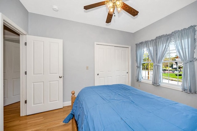 bedroom with baseboards, a ceiling fan, a closet, and light wood-type flooring
