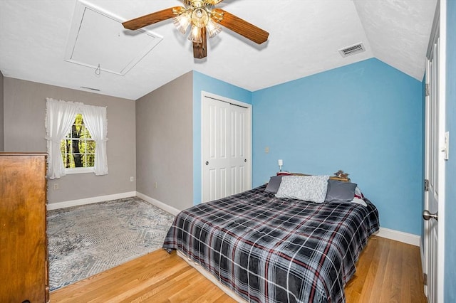 bedroom featuring ceiling fan, attic access, visible vents, wood finished floors, and baseboards