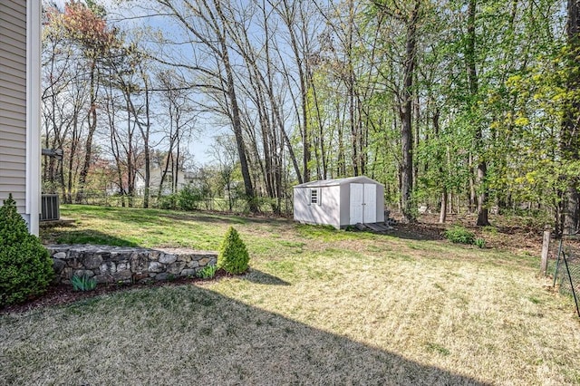 view of yard with central AC unit, a shed, an outbuilding, and fence