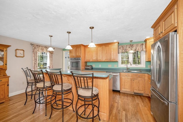 kitchen with light wood-type flooring, a sink, appliances with stainless steel finishes, and a kitchen island