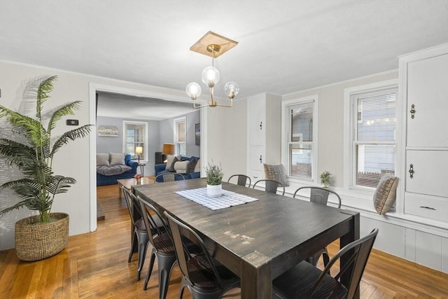 dining area with crown molding, light wood-style flooring, and a notable chandelier