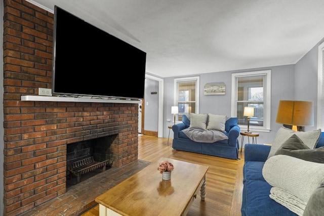 living area featuring a brick fireplace, baseboards, and wood finished floors