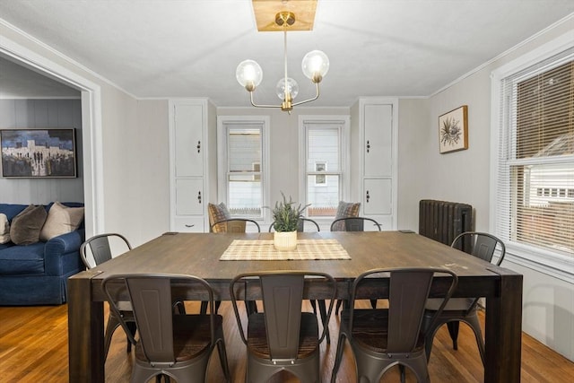 dining space featuring ornamental molding, plenty of natural light, wood finished floors, and an inviting chandelier