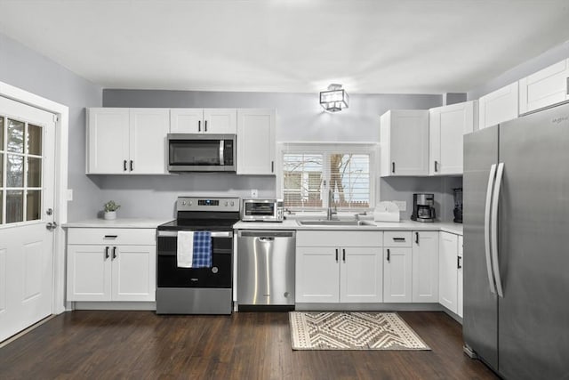 kitchen featuring white cabinets, appliances with stainless steel finishes, light countertops, and a sink