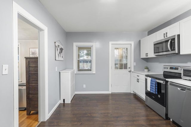 kitchen featuring baseboards, white cabinets, appliances with stainless steel finishes, dark wood-style flooring, and light countertops