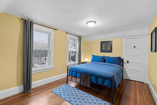 bedroom featuring lofted ceiling, baseboards, and wood finished floors