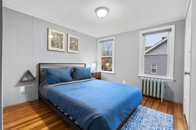 bedroom with radiator heating unit and wood finished floors