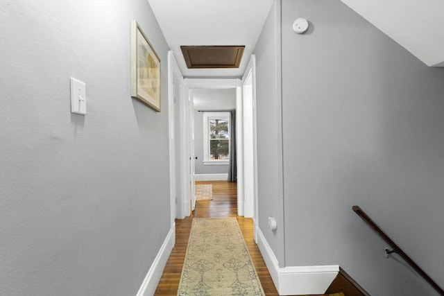 hallway featuring attic access, baseboards, dark wood finished floors, and an upstairs landing